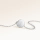 Baksidan av ett runt silverhalsband med personlig gravyr av ett datum