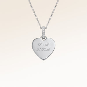 Close-up of minimalist heart-shaped heart pendant in silver with white zircons and space for personalized engraving on the front and back