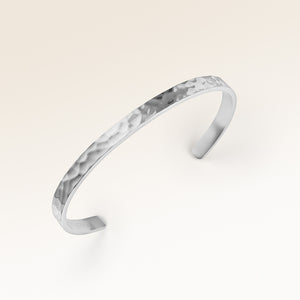 Close-up of minimalist bangle bracelet in silver with rippled wave surface and space for personalized engraving
